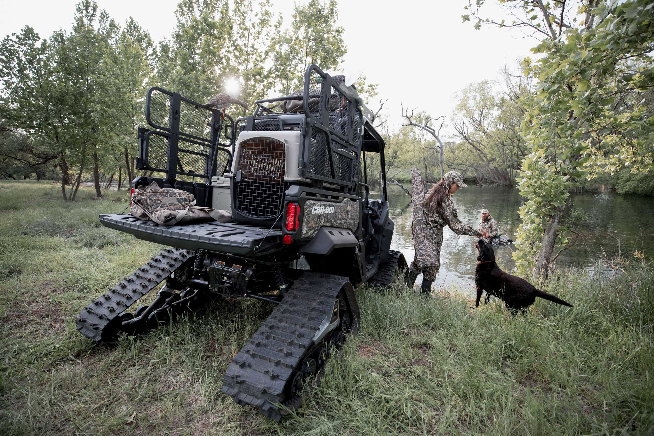 Rear view of a custom hunting Can-Am Defender and a couple and their dog